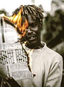 A man holding a burning newspaper in rural Zimbabwe, symbolizing protest.