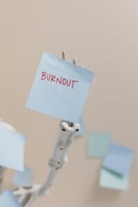 A skeleton holding a sticky note reading 'Burnout', symbolizing workplace stress.
