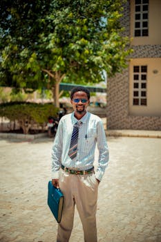 Confident young man holding a file outdoors, embracing urban business style.