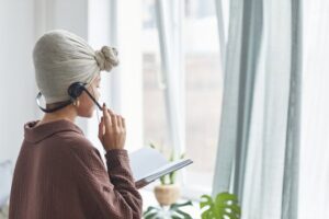 Side view of a woman in a turban using a headset while reading at home.